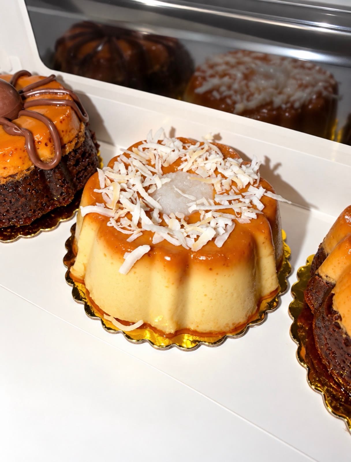 Coconut-topped chocoflan packaged in a white bakery box