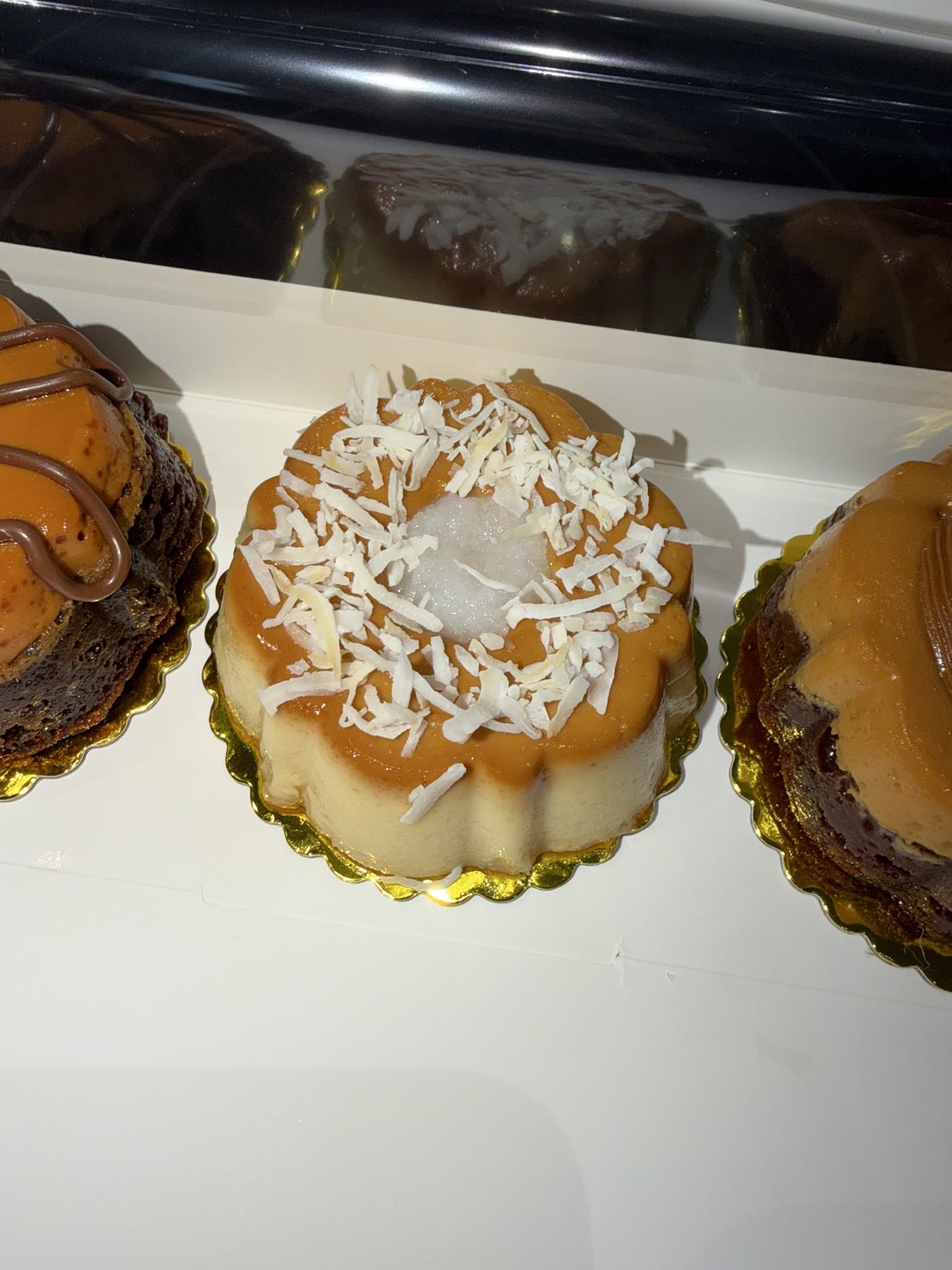 Mini coconut-topped chocoflans arranged in a bakery box