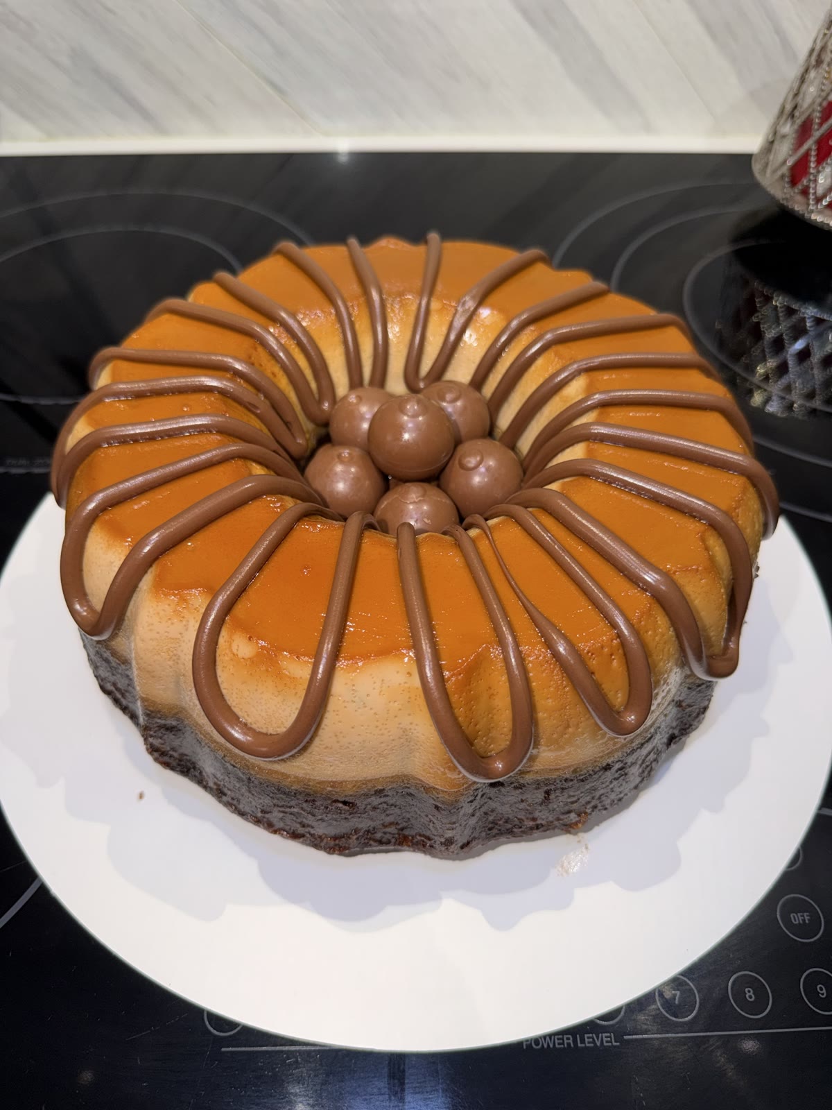 Close-up of a large chocoflan with chocolate drizzle and round chocolate candies