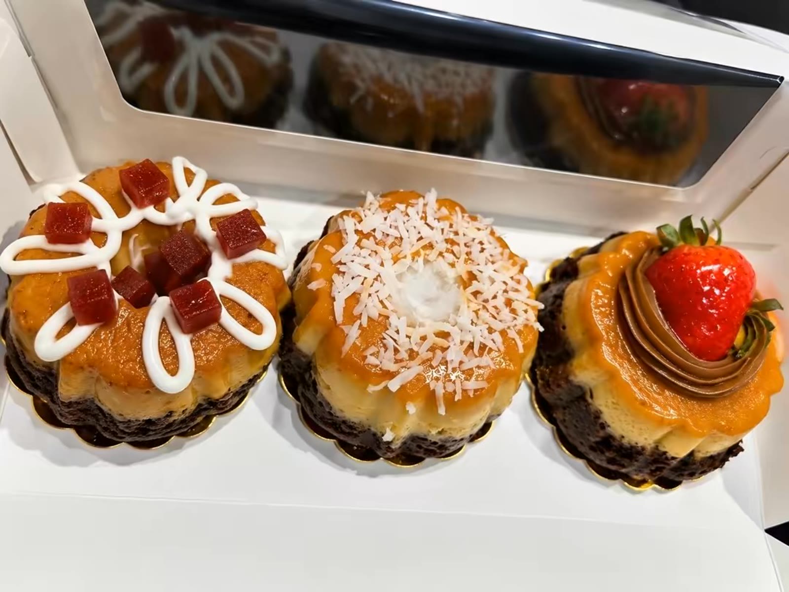 Three mini chocoflans with assorted toppings in a box